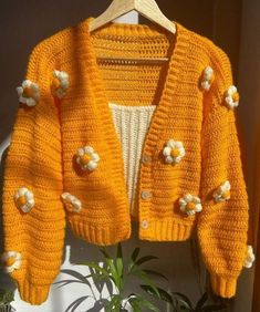 a yellow knitted jacket with white flowers on it