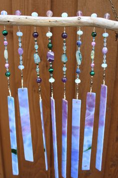 a wind chime hanging from a tree branch with beads and stones on it's sides