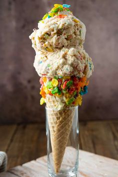 an ice cream cone with sprinkles and candies in it on a wooden table