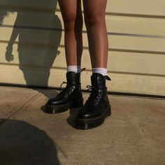 a person wearing black boots and white socks standing in front of a garage door