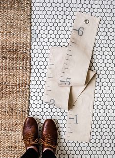 a pair of brown shoes sitting on top of a floor next to a measuring tape