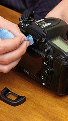 a man is cleaning his camera with a blue cloth on the table next to it