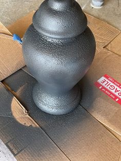 a gray vase sitting on top of a cardboard box