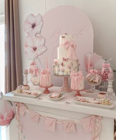 a table topped with a white cake and pink decorations