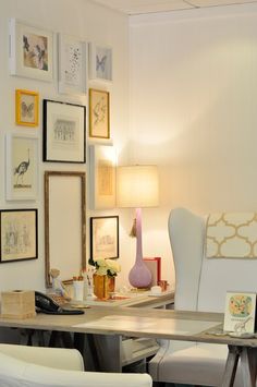 a white chair sitting in front of a table with pictures on the wall behind it