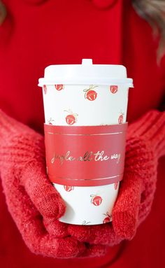 a woman in red sweater holding up a coffee cup with the words apple on it