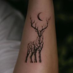 a tattoo on the arm of a person with trees and a moon in the background