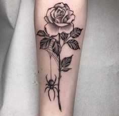 a black and white rose tattoo on the right arm, with leaves around it's stems