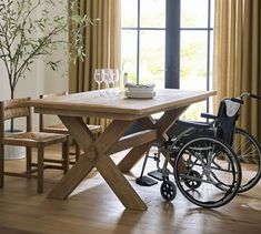 a wooden table with two chairs next to it and a wheelchair parked in front of the table