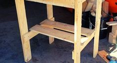 a wooden work bench sitting on top of a cement floor next to an orange bucket