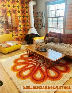 a living room filled with furniture and a fire place next to a large window on top of a hard wood floor