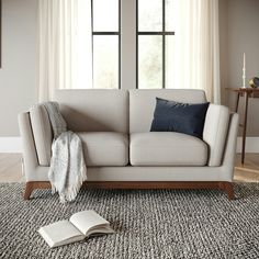 a living room scene with focus on the couch and book lying on the floor next to it