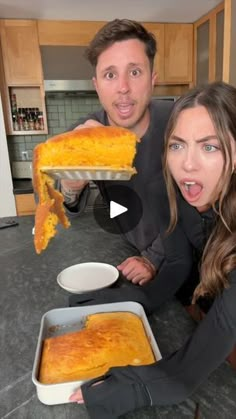 a man and woman holding up a large piece of cheesy pizza in front of them