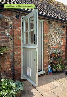 an open door to a brick building with potted plants in the front and side