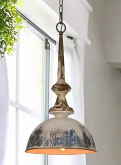 an old light hanging from a ceiling in a room with white walls and windows behind it