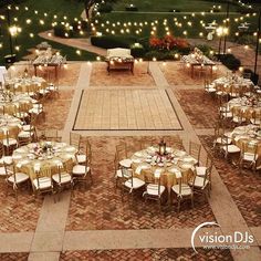 tables and chairs are set up for an outdoor event with lights strung from the trees