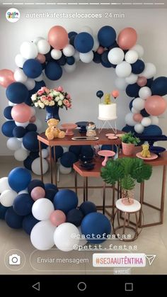 a table topped with balloons and flowers next to a cake on top of a table