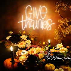 a table topped with flowers and candles next to a sign that says give thanks on it