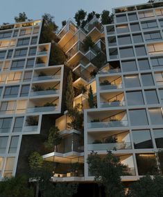 the building has many balconies and plants growing on it's sides at night