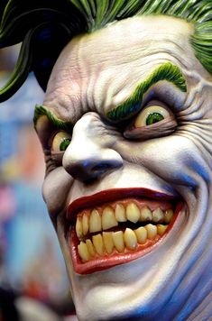 a close up of a clown's face with teeth and green hair on it