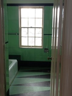 an empty bathroom with green walls and black and white checkered flooring on the floor