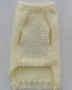 a white knitted baby sweater on a white tablecloth with the bottom half folded up