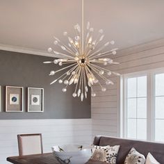 a living room with a couch, table and chandelier hanging from the ceiling