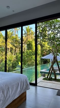 a bed sitting in a bedroom next to a large glass window overlooking a lush green forest