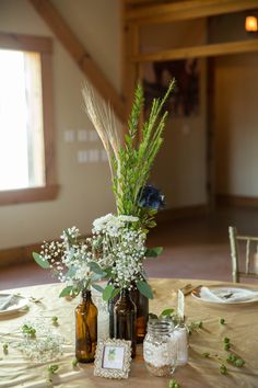 there are two bottles with flowers in them on the table