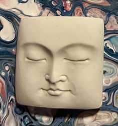 a ceramic face with eyes closed on a marble background