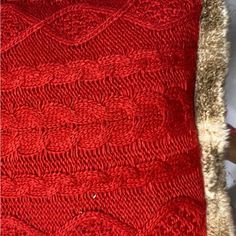 a red knitted pillow with a fur trim