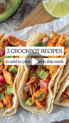 three crockpot tacos sitting on top of a piece of paper next to an avocado