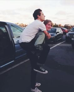 a man is holding onto a woman's back in a parking lot