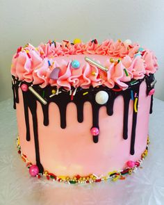 a birthday cake with pink frosting and sprinkles on the top is sitting on a table