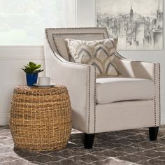 a living room with a wicker stool and white chair in front of a window