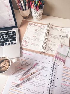 an open notebook sitting on top of a desk next to a laptop computer and cup of coffee