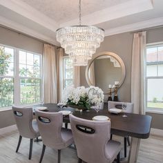 a dining room table with chairs and a chandelier hanging from it's ceiling