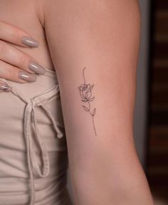 a woman's arm with a small flower tattoo on the left side of her arm