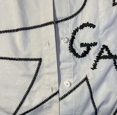 a white shirt with black letters on the front and back buttons, along with an arrow drawn across the chest