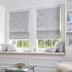 a living room with two windows covered in roman shades