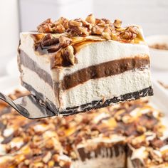 a piece of cake is being lifted from a white plate with other desserts on it