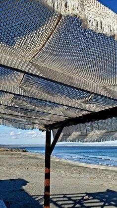 an open umbrella on the beach with water in the background