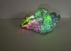 a colorful rock sitting on top of a table next to a white wall in the background