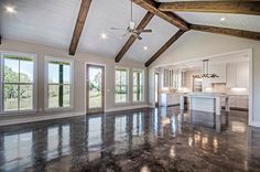 an empty living room with large windows and wood beams on the ceiling is pictured in this image