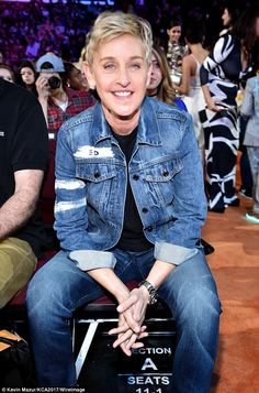 a man sitting in front of a crowd at a basketball game wearing a jean jacket