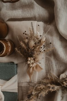 an arrangement of dried flowers and other items on a linen tablecloth with white ribbon