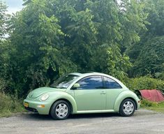 a small green car parked in front of some trees