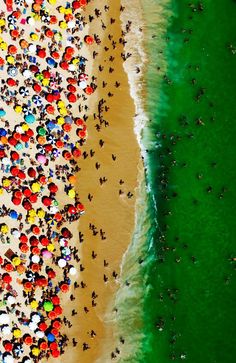 an aerial view of people on the beach with umbrellas in the sand and green water