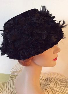 "Vintage 1950s Black Velvet Bucket style hat. Has a stiff lace base. Covered in Black Velvet petals and feathers. CONDITION: No issues noted. INSIDE CIRCUMFERENCE: 25\" This hat is a style that sits on the top of your head. You will see in the pictures (of the inside out of the hat) the part of the hat that will hold the hat in place. It will fit many head sizes. It even fits me! Height-6\" **WE APOLOGIZE~BUT WE CAN NO LONGER SHIP TO ITALY OR SPAIN. WE HAVE INCURRED TOO MANY ISSUES WITH SHIPPING Evening Costume Hat With Feathers, Vintage Adjustable Feather Headpieces, Vintage Adjustable Headpieces With Feathers, Adjustable Vintage Headpieces With Feathers, Vintage Feathered Headpieces For Vintage Events, Vintage Feather Headpieces For Vintage Events, Vintage Evening Fascinator With Feathers, Vintage Formal Headpieces For Spring, Vintage Feathered Costume Hats For Evening