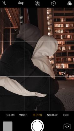 a person wearing a hoodie sitting on a bench in front of a building at night